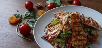 Delicious grilled chicken salad served with fresh tomatoes and walnuts on the side.