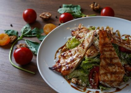 Delicious grilled chicken salad served with fresh tomatoes and walnuts on the side.